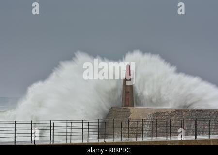 Onda di tempesta oltre il vecchio faro e il molo di Viavelez nelle Asturie, Spagna. Foto Stock