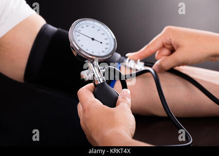 Medico controllando la pressione del sangue del paziente Foto Stock