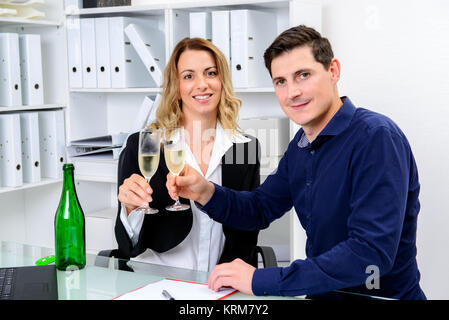 Giovane imprenditore e imprenditrice celebrando insieme in ufficio Foto Stock