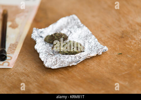 Chiudere fino sulla marijuana in foglio di stagno con il tubo, Euro denaro in background Foto Stock