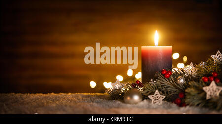 Candela che brucia e decorazione di Natale sulla neve e lo sfondo di legno, elegante basso-chiave girato con atmosfera di festa Foto Stock