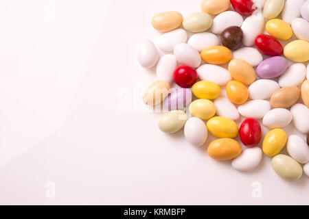 Mandorle zuccherate colorate disposte su fondo bianco Foto Stock
