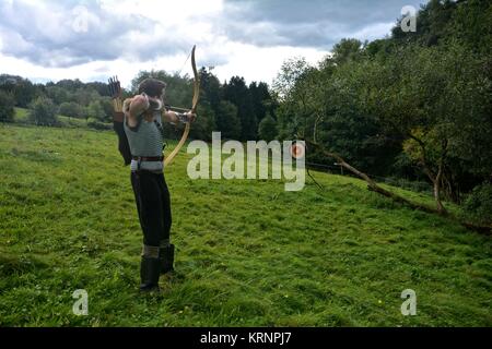 archer medievale, puntando con prua e freccia al disco di paglia in natura Foto Stock