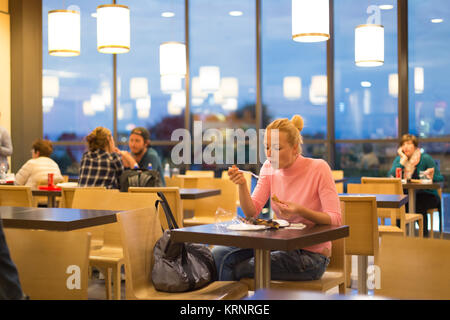 Giovane donna di mangiare pizza all'aeroporto ristorante mentre si è in attesa della partenza del volo. Foto Stock