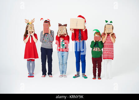 I bambini tenendo il natale presente nella parte anteriore della loro faccia Foto Stock