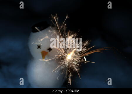 Un po' carino pupazzo di neve con un sparkler NELLA NOTTE BUIA Foto Stock