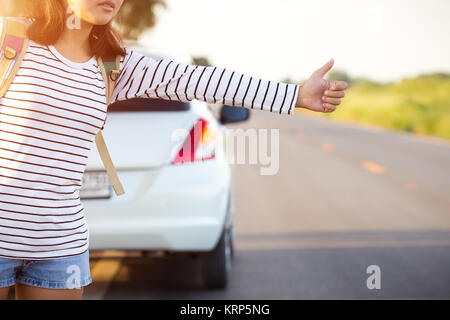 Donna autostop in cerca di aiuto con il suo Broken auto sulla strada Foto Stock