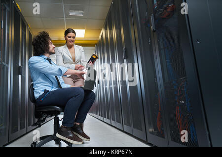 Due giovani tecnici al lavoro in un centro dati sulla manutenzione del server Foto Stock