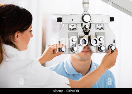 All'ottico optometrista femmina Phoropter di regolazione per il paziente Foto Stock