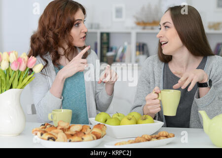 Due femmina sorridente amici seduti a tavola Foto Stock