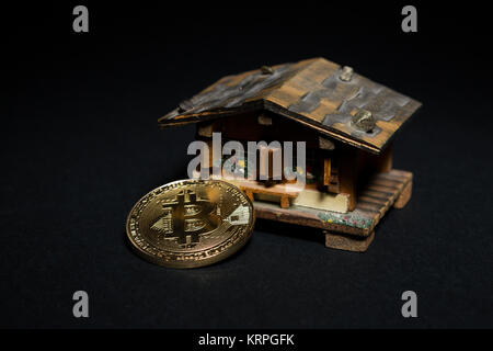 Acquistare e vendere beni immobili per bitcoins concetto con piccoli cottage house e metallo golnden moneta di bit Foto Stock