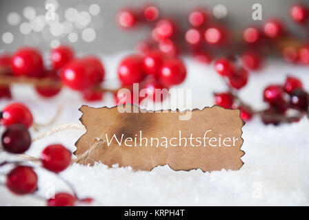 Bruciò etichetta con testo in tedesco significa Weihnachtsfeier festa di Natale. Red decorazione di Natale sulla neve. Parete in cemento come sfondo bokeh di fondo con effetto. Card per i migliori auguri di Buon Natale Foto Stock