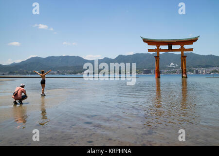 Miyajima - Giappone, 26 Maggio 2017: Rosso Torii gate del santuario di Itsukushima in mare con la bassa marea di turisti nei pressi di Miyajima Foto Stock