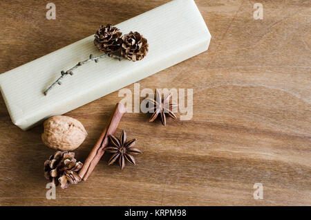 Vintage Kraft Natale confezione regalo in stile rustico decorata con Pigne su sfondo di legno. Foto Stock