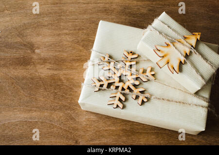 Natale scatole Kraft con doni decorate in stile rustico su sfondo di legno. Foto Stock