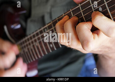 Primo piano sul musicista la mano formando una corda su una chitarra elettrica. Foto Stock