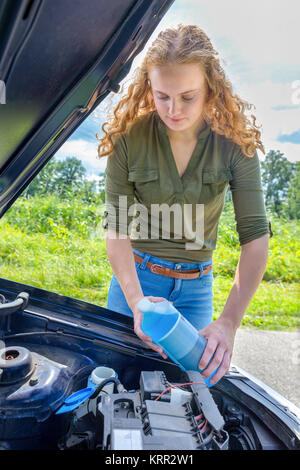 La donna caucasica riempimento serbatoio auto con il parabrezza del liquido tergivetro Foto Stock