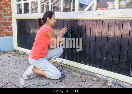 Donna al lavoro su legno della casa con affilatore elettrico Foto Stock