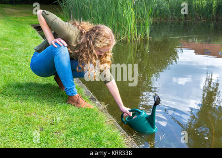 Giovane donna olandese verde di riempimento caster con acqua in natura Foto Stock