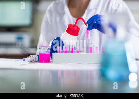 Le mani di un ricercatore femmina svolgendo attività di ricerca in un laboratorio di chimica (colore immagine dai toni shallow DOF) Foto Stock