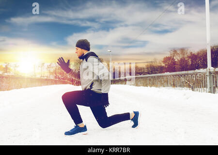 L'uomo esercita e facendo squat sul ponte di inverno Foto Stock