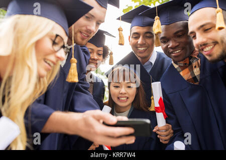 Gli studenti o laureati con diplomi e lo smartphone Foto Stock