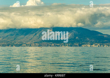 Barca in mare ionio nella parte anteriore delle scogliere delle coste dell'isola di Zante Foto Stock