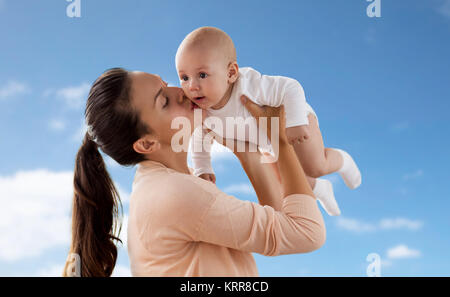 Felice madre baciare little baby boy su sky Foto Stock