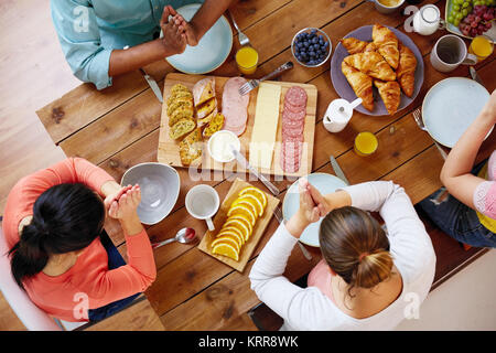 Gruppo di persone a tavola pregare prima del pasto Foto Stock