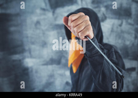 Incappucciati membro della gang criminale con sciarpa sulla faccia con un cacciavite come arma Foto Stock