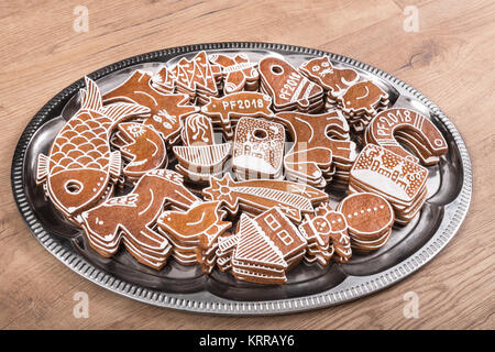 Tradizionale gingerbreads natale di varie forme su una tavola di legno. Pile di carino e decorato a mano i cookie impilati su un lucido vassoio d'argento Foto Stock