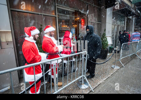 I partecipanti in SantaCon preparare per mostrare il loro ID alla Ainsworth bar nel quartiere di Chelsea di New York sabato 9 dicembre, 2017. SantaCon, principalmente un pub crawl a Santa e altro Natale costumi correlati, attrae migliaia di masqueraders andando da bar a bar. (© Richard B. Levine) Foto Stock