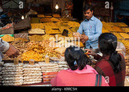 Un fornitore serve i clienti al suo namkeen (snack salati e dolci stallo nella città di Lucknow, India Foto Stock