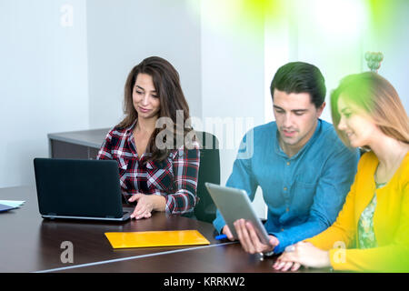 Team di persone motivate, utilizzando vari dispositivi ad una fusione di avvio. concetto, il lavoro di squadra Foto Stock