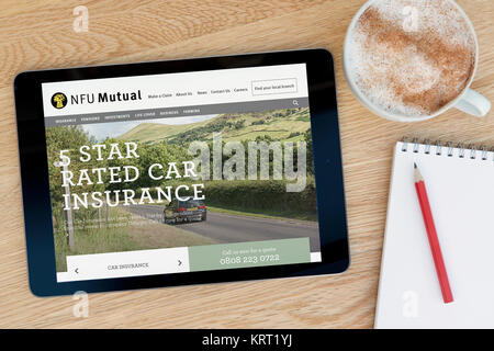 La NFU mutuo sito web su un iPad dispositivo tablet pc che si appoggia su una tavola di legno accanto a un blocco note e matita e una tazza di caffè (editoriale solo) Foto Stock