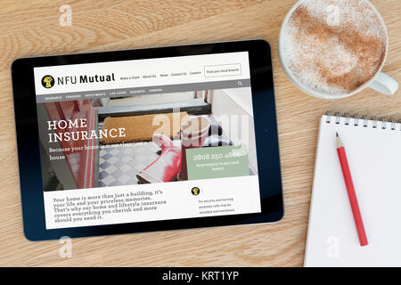La NFU mutuo sito web su un iPad dispositivo tablet pc che si appoggia su una tavola di legno accanto a un blocco note e matita e una tazza di caffè (editoriale solo) Foto Stock