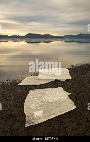 Tre ice floes sulla sabbia scura sulla spiaggia norvegese. Mare calmo, la foschia e la nebbia. Hamresanden, Kristiansand, Norvegia Foto Stock