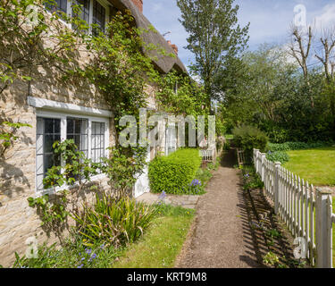 Un percorso a fianco della parte anteriore di un cottage con tetto di paglia, Halford, vicino a Shipston on Stour, Warwickshire, Inghilterra, Regno Unito Foto Stock