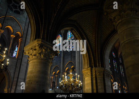 Gli interni della cattedrale de Notre Dame sull'Ile de la Cite a Parigi Francia, con illuminazione drammatica, un lampadario e finestre di vetro colorato Foto Stock