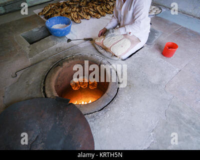 Armenian pane cotto in un tonir, Yerevan, Armenia. Una donna che cuoce tradizionale pane armeno all'interno di un tradizionale di pietra tonir sul pavimento Foto Stock