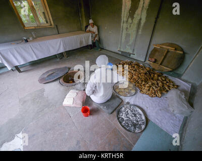 Armenian pane cotto in un tonir, Yerevan, Armenia. Una donna che cuoce tradizionale pane armeno all'interno di un tradizionale di pietra tonir sul pavimento Foto Stock