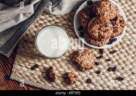 Un bicchiere di latte e farina di avena cookie su piastra bianca Foto Stock