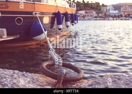 Anello di ferro con corda allacciate su un dock con città sfocata sullo sfondo Foto Stock