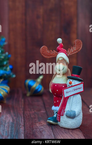 Sfondo di Natale con le renne e un pupazzo di neve su un marrone di sfondo di legno Foto Stock