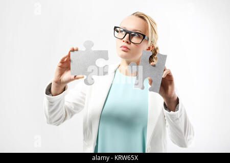 Una donna attraente in abbigliamento business corrisponde i pezzi del puzzle. Foto Stock