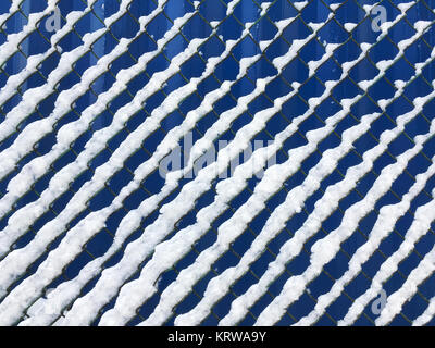 Catena collegamento recinto coperto con fresco bianco della neve contro sfondo blu Foto Stock