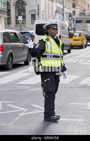 Una poliziotta dirigere il traffico sulla Quinta Avenue e la 43rd Street nel centro di Manhattan, New York City. Foto Stock