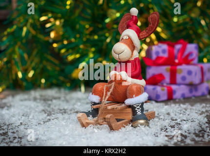 Giocattolo di Natale cervi in vacanza vestiti sulla slitta di legno tra la neve Foto Stock