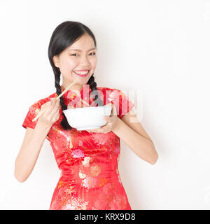 Oriental woman in red cheongsam mangiare con bacchette Foto Stock