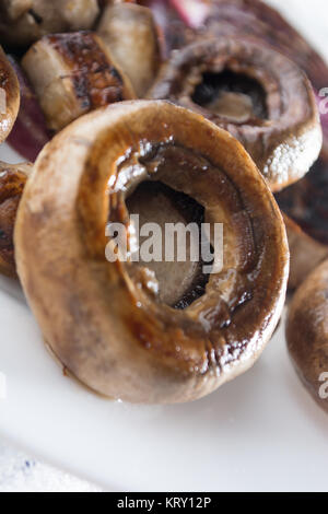 Close up arrosto funghi succosa con cipolla sulla piastra bianca Foto Stock